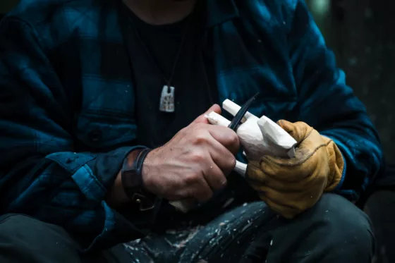 Close up of man carving branch with knife in nature