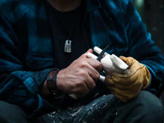 Close up of man carving branch with knife in nature